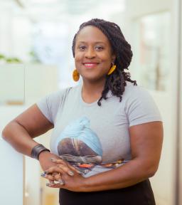 Priscilla Ocen headshot, standing with hands clasped