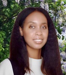 Headshot in white shirt in front of greenery