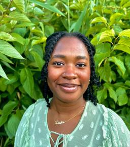 Headshot of Hafeezat in pale green shirt in front of bright green foliage