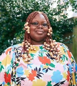 Headshot in floral shirt in front of green foliage