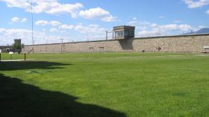 A prison yard with grass, stone walls, and a tower.