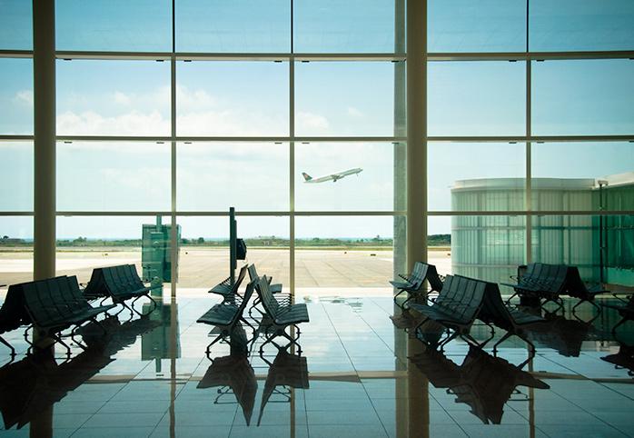 Empty airport gate, a plane takes off in the background