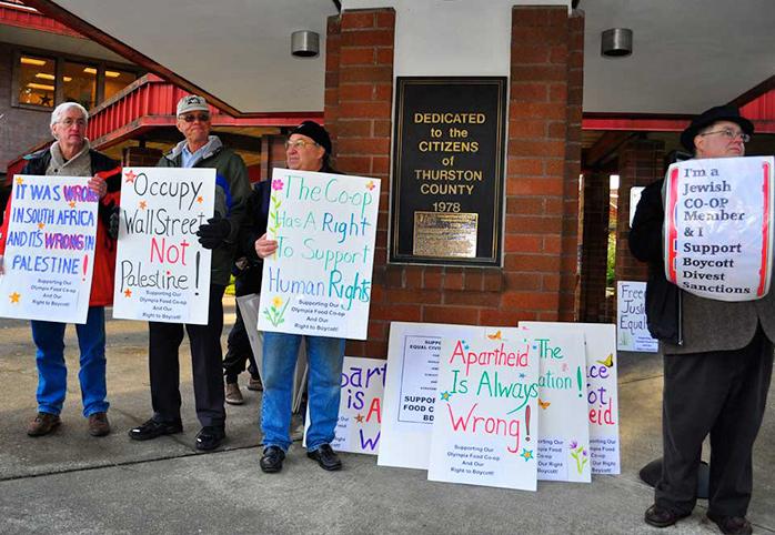 Protestors hold signs in support of the Olympia Food Coop's right to boycott Israeli products