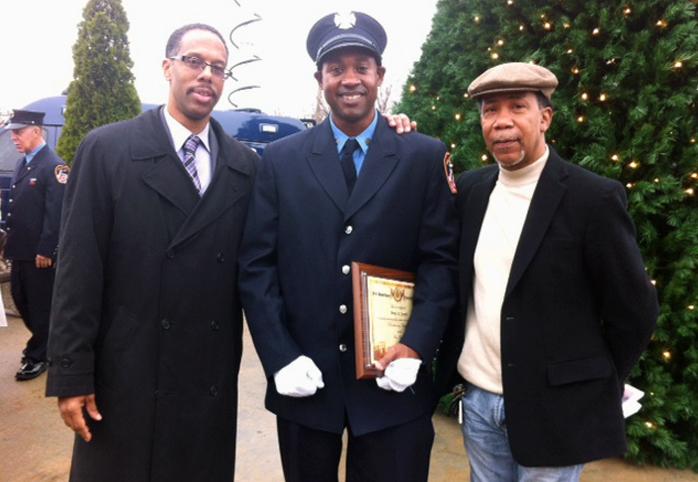 A Black firefighter graduates, smiling