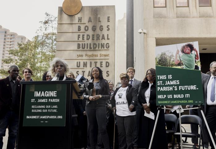 Co-founder and co-director of Inclusive Louisiana Gail Leboeuf talking into a microphone, standing behind a podium, in front of a crowd of people.